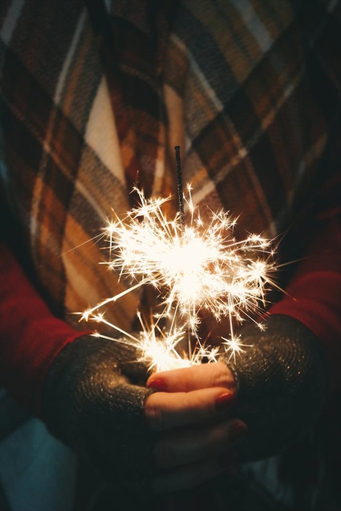 Close-up of hands holding a sparkler, evoking a warm holiday atmosphere.