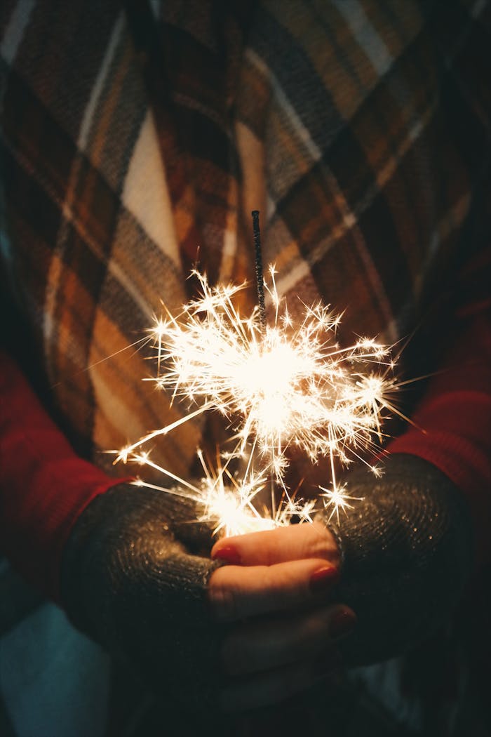 Close-up of hands holding a sparkler, evoking a warm holiday atmosphere.