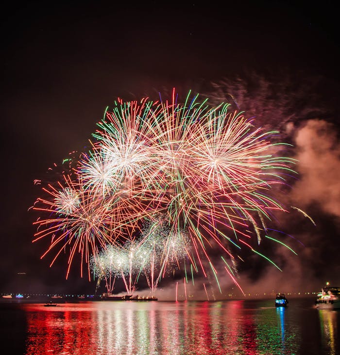 cta-02 Colorful fireworks illuminating the night sky above a serene water body, creating a festive atmosphere.
